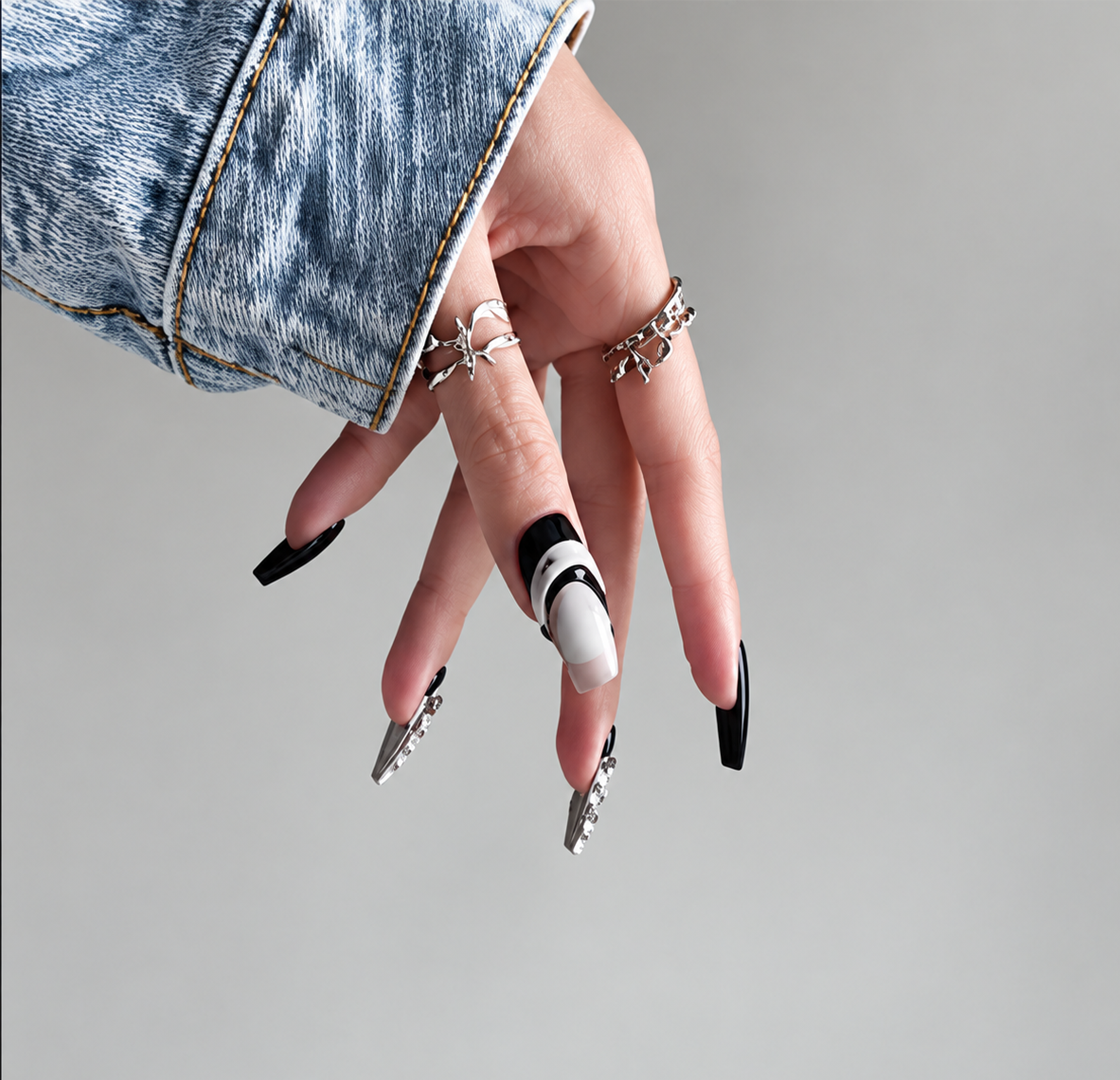 Manicure con unghie nere e bianche, decorazioni e anelli argentati